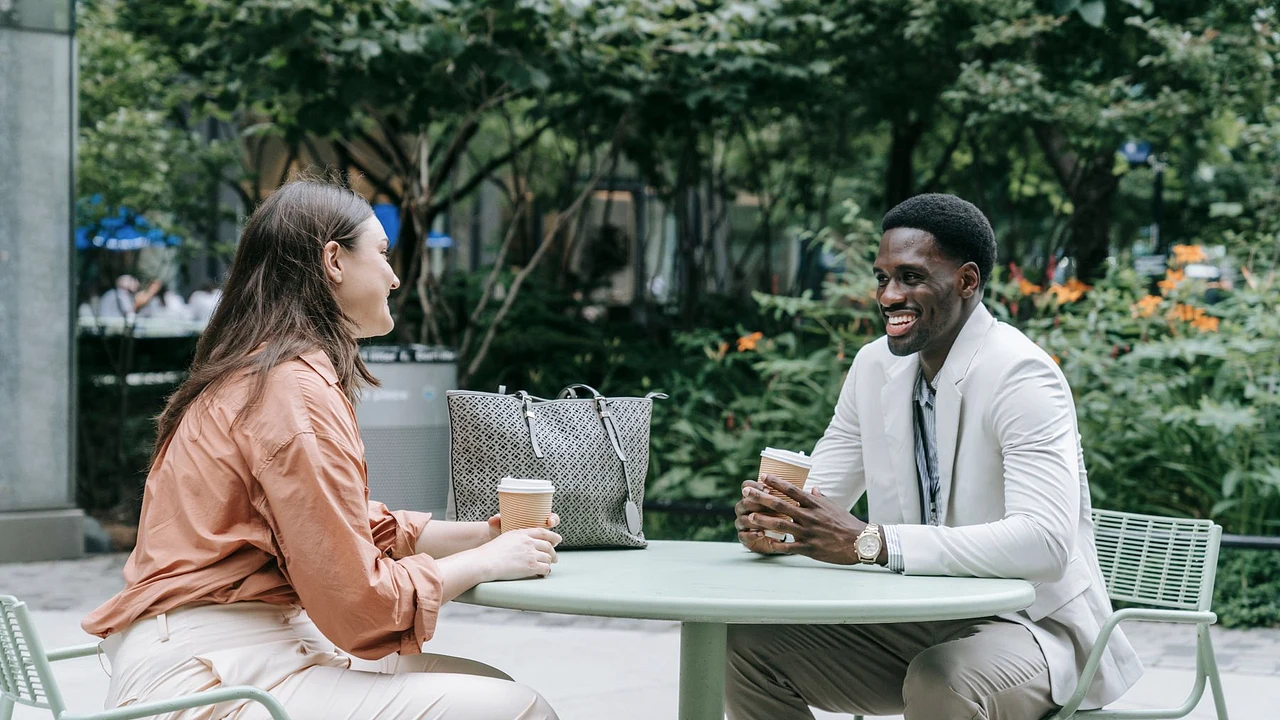 Two adults listening and talking with each other over coffee at an outdoor cafe