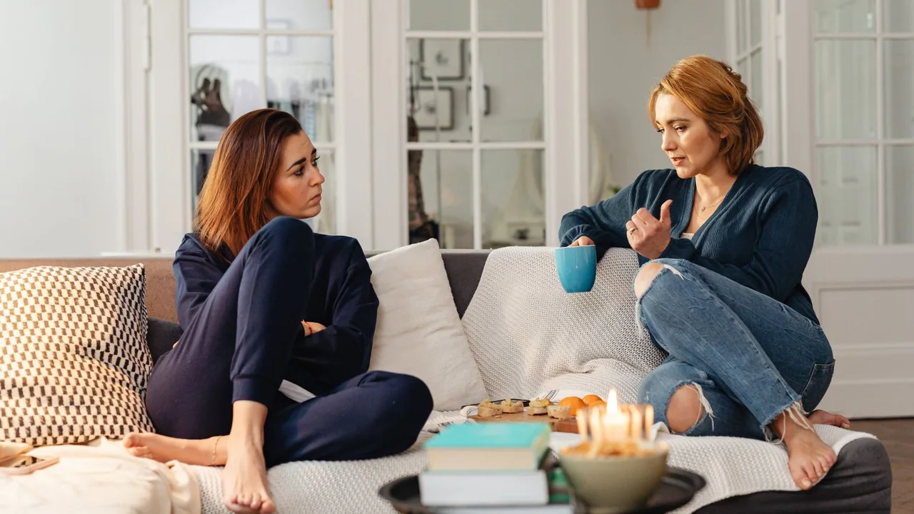 One friend sharing something personal while another listens during a quiet conversation at home