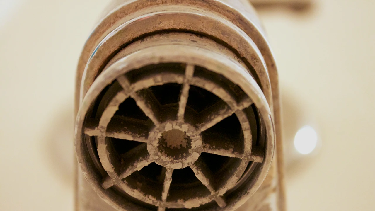 Close view of heavy white calcification on the outlet of a metal bath tap