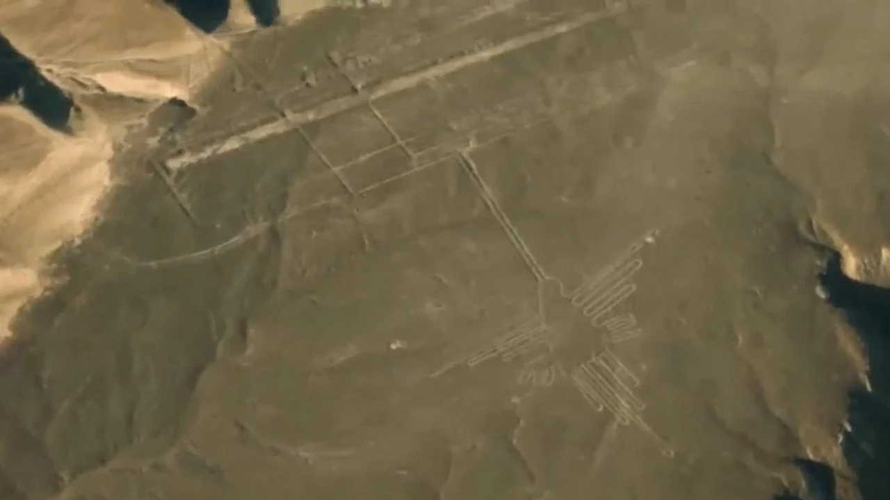Aerial view of a large bird-shaped Nazca geoglyph and straight lines across the desert plain in Peru