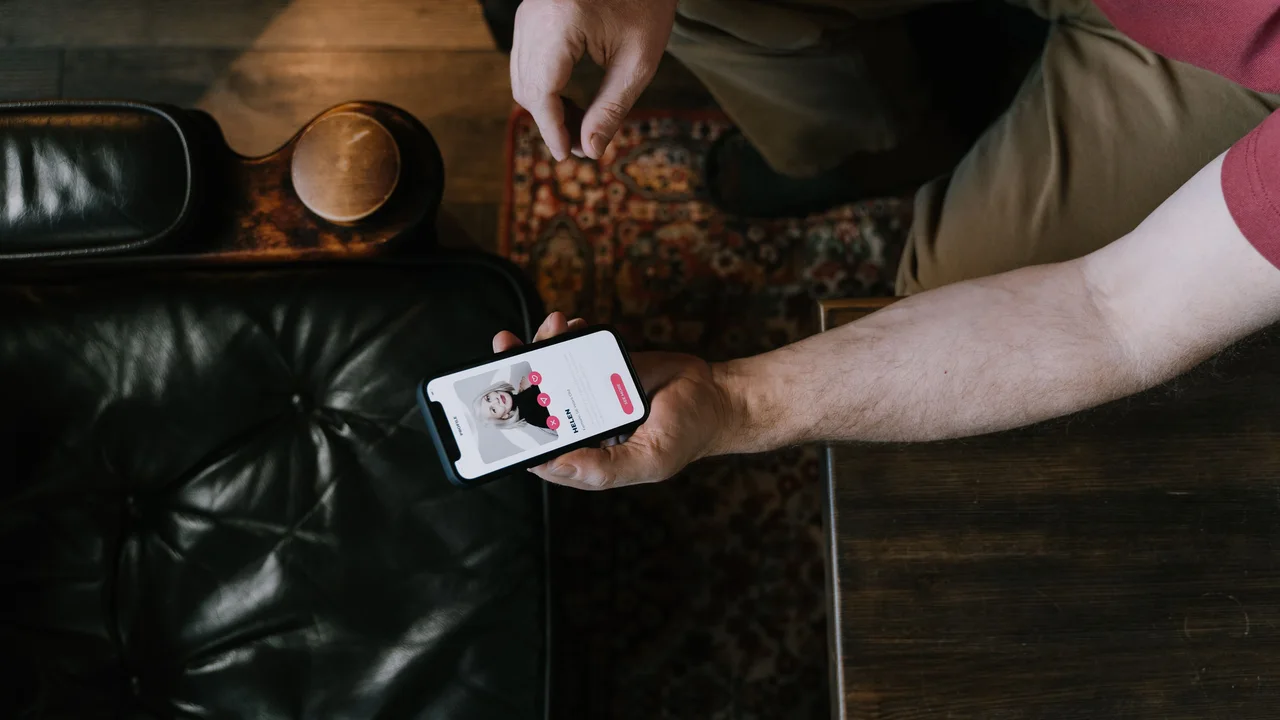 A person viewing a dating profile on a smartphone while keeping the device in their own hands