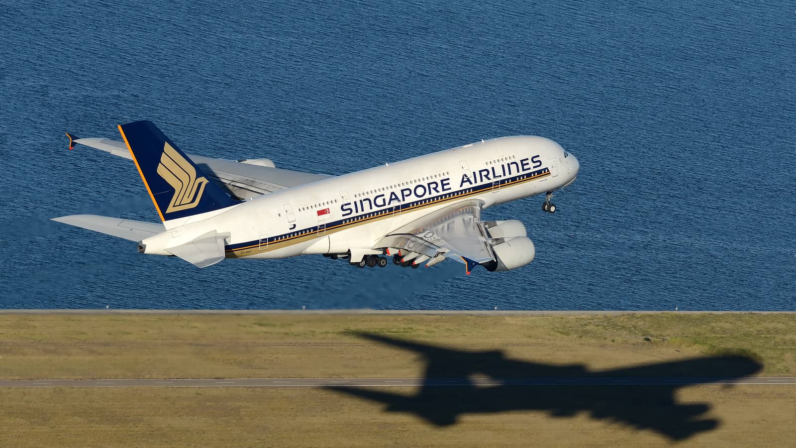 A Singapore Airlines Airbus A380 lifting from Sydney Airport with its four engines, double deck and shadow clearly visible