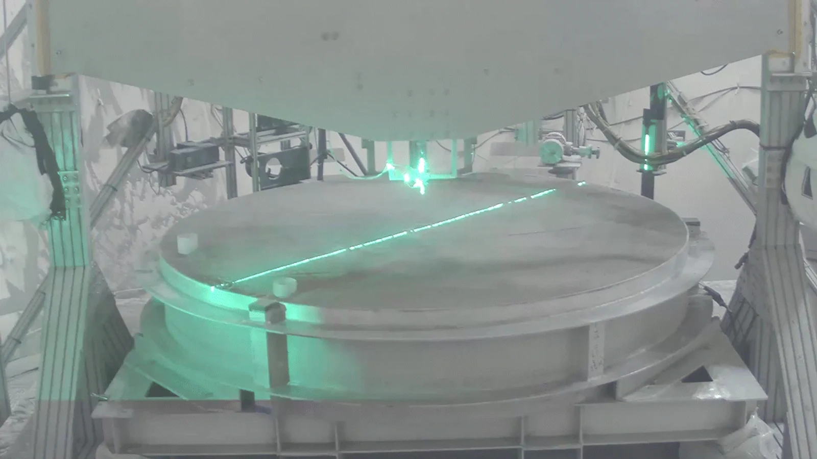 NASA test-run frame showing an ethane plume simulator firing into simulated lunar dirt inside a vacuum chamber