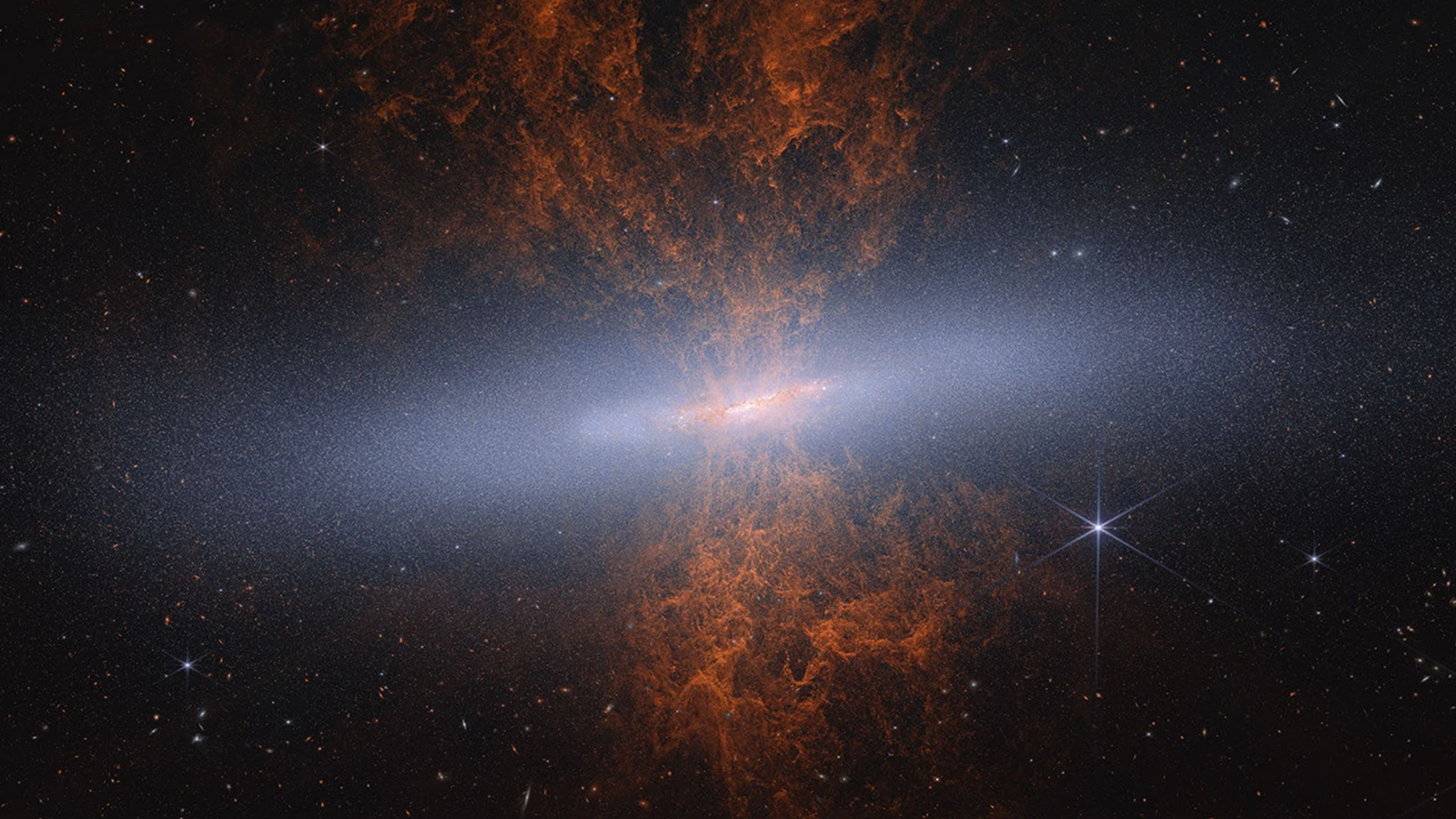 Near-infrared NASA Webb view of the edge-on Cigar Galaxy M82, with its bright disk and red-orange starburst plumes rising above and below